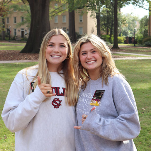 Student wearing a back pack looking over the the wrought iron fence onto the lush green space of the Historic Horseshoe. 