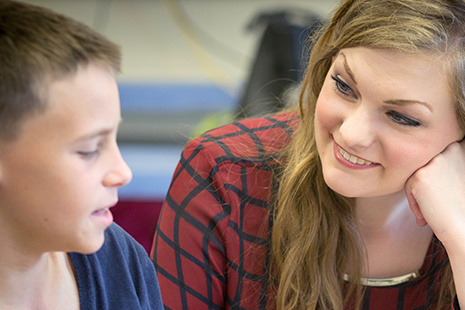 A female teacher smiles at a male student
