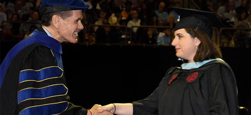 Dean Pedersen shakes Michelle's hand at commencement