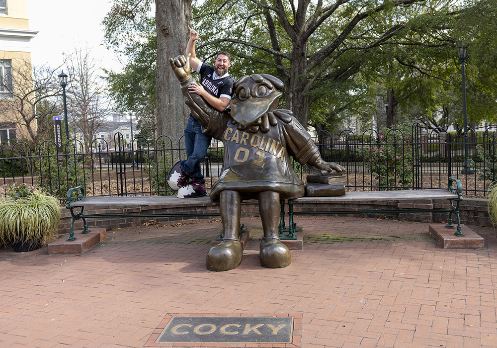 Jamie Ballentine poses with the bronze Cocky statue on USC's campus.