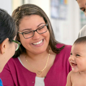 A health care provider greets a mother and her infant.
