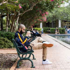 Student sitting at the Thomas Cooper Library fountains on his phone.